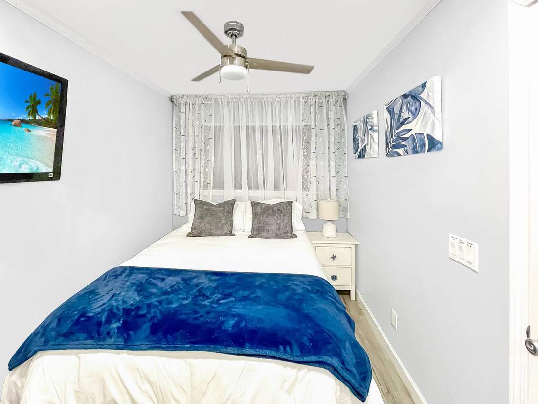 Queen bedroom with wall-mounted TV and ceiling fan
